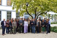 Group of October Assembly posing in front of a tree in the courtyard of the Sint Baafshuis